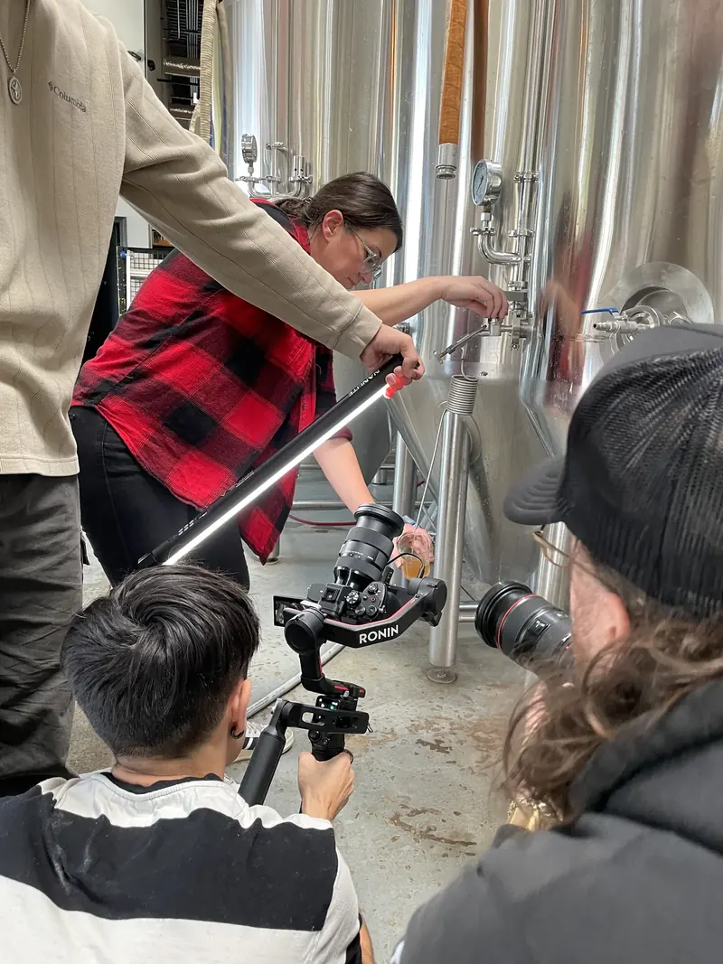 Camera crew capturing a close view beside stainless-steel tanks